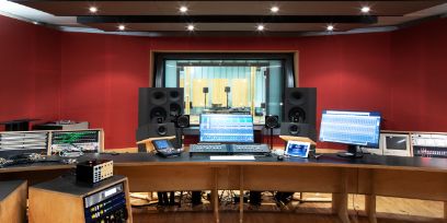 A room with a mixing console, loudspeakers and other electronic devices.