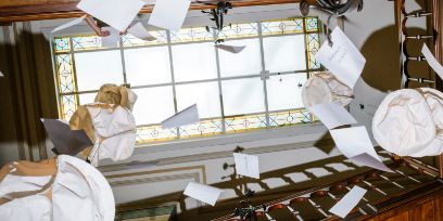 Photo prise dans le bâtiment du SLI, du bas vers le haut, à travers la cage d'escalier. Des papiers flottent dans les airs, comme dans un mobile. Tout en haut, on aperçoit les belles vitres du toit.