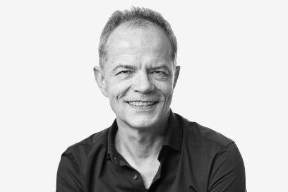Ein schwarz-weiss-Bild von Wolfram Heberle. Der Mann lächelt dabei in die Kamera und trägt ein schwarzes Hemd.