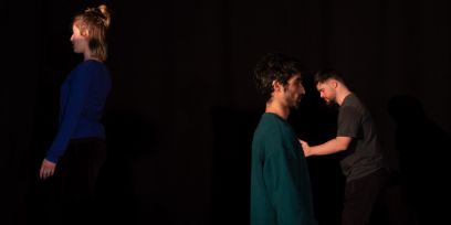 Drei Personen stehen vor schwarzem Hintergrund.