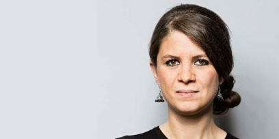 Eine Frau vor grauem Hintergrund blickt geradeaus in die Kamera.