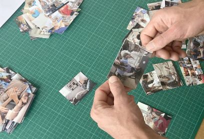 Auf einem Tisch sind verschiedene Fotos verteilt. Zwei Hände halten ein Foto.