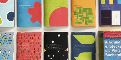 Fotografie der Titelbilder der neun Hefte sowie der Sammelbox von «Punkt für Punkt: Alex und Lilani entdecken die Welt der Buchstaben».