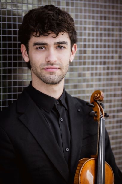 Ein Mann blickt direkt in die Kamera. Er hält eine Violine.