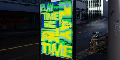 Das Playtimeplakat in den Farben blau, gelb und grün steht an einer leeren Strasse. Im Hintergrund ist ein Rennvelo an einen Pfosten angelehnt.