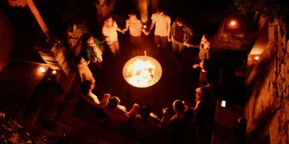 Menschen im Kreis stehend, Hände haltend um ein Feuer. Von oben fotografiert