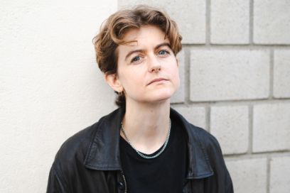 Saskia Winkelmann schaut in die Kamera. Sie steht vor einer Hausmauer und trägt ein schwarzes Oberteil.