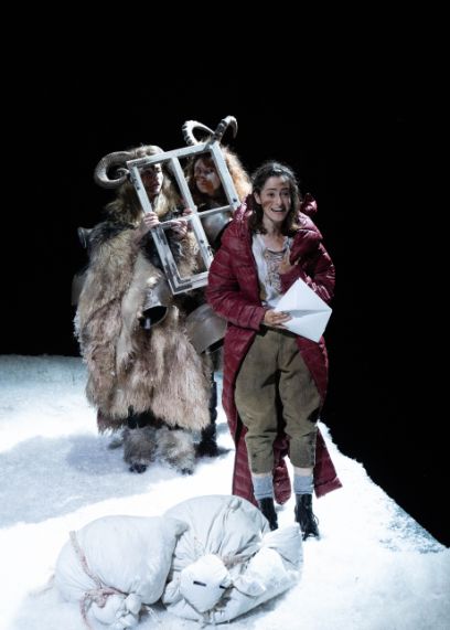 Szene auf der Bühne mit weissem Kunstschnee und der Figur Heidi mit langem Mantel.
