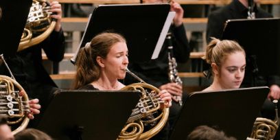 Zwei Frauen sitzen in einem Orchester und spielen auf ihren Blasinstrumenten.