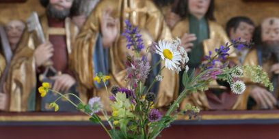 Wildblumen sind vor einem Ausschnitt des Flügelaltars von Brienz zu sehen.
