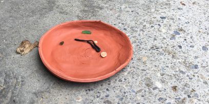 Ein Teller aus Ton auf dem Boden.