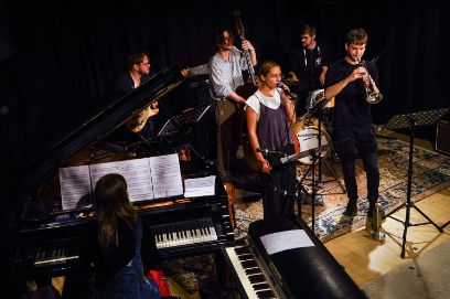 Musicians with different instruments stand on stage and play.