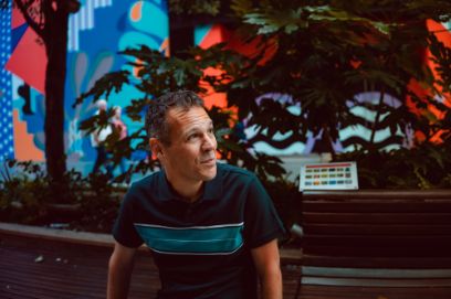 Portrait von Matthew Shlomowitz, vor farbigem Hintergrund mit Pflanzen