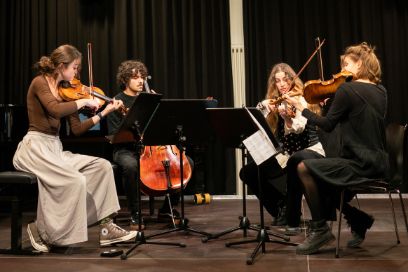 Ein Streichquartet, bestehend aus drei Frauen und einem Mann, musiziert auf einer Bühne.