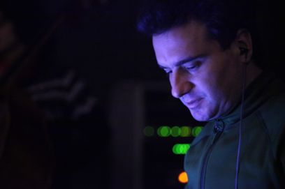 Side view of a man's face illuminated in blue. Different coloured indicator lights can be seen in the dark background.