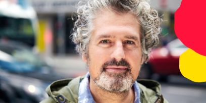 Ein Mann mit grauen, lockigen Haaren und Bart schaut freundlich in die Kamera.