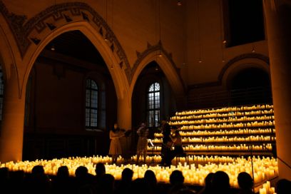 Auf einer Bühne in einer Kirche musiziert von brennenden Kerzen umgeben ein Streichquartett.