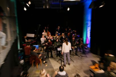 Eine Musikgruppe auf der Bühne, schräg von oben mit Bewegungsunschärfe aufgenommen.