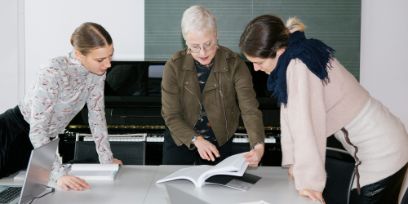 drei Personen schauen in ein Heft