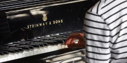 Auschschnitt Klaviertasten, die Hand einer Person in gestreiftem Oberteil 