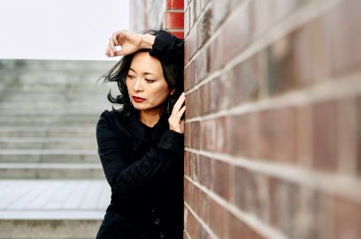 Portraitaufnahme von Rei Nakamura, angelehnt an einer Wand