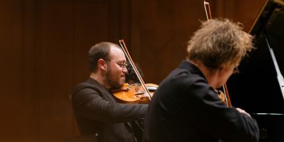 Zwei Männer spielen Geige.