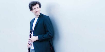 Halbprofilaufnahme eines Mannes in Schwarzweiss vor schwarzem Hintergrund.