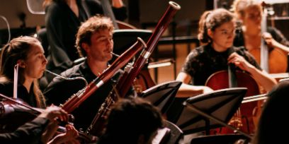 Ausschnitt aus einem Orchester, zu sehen sind Fagottist*innen und Cellist*innen.