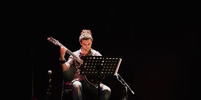 Person an Gitarre, sitzend von vorne