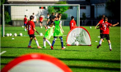 Kinder spielen Fussball mit grossen und zwei kleinen Toren