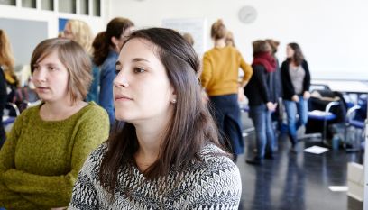 Person hört interessiert zu, weitere unscharfe Personen im Vordergrund
